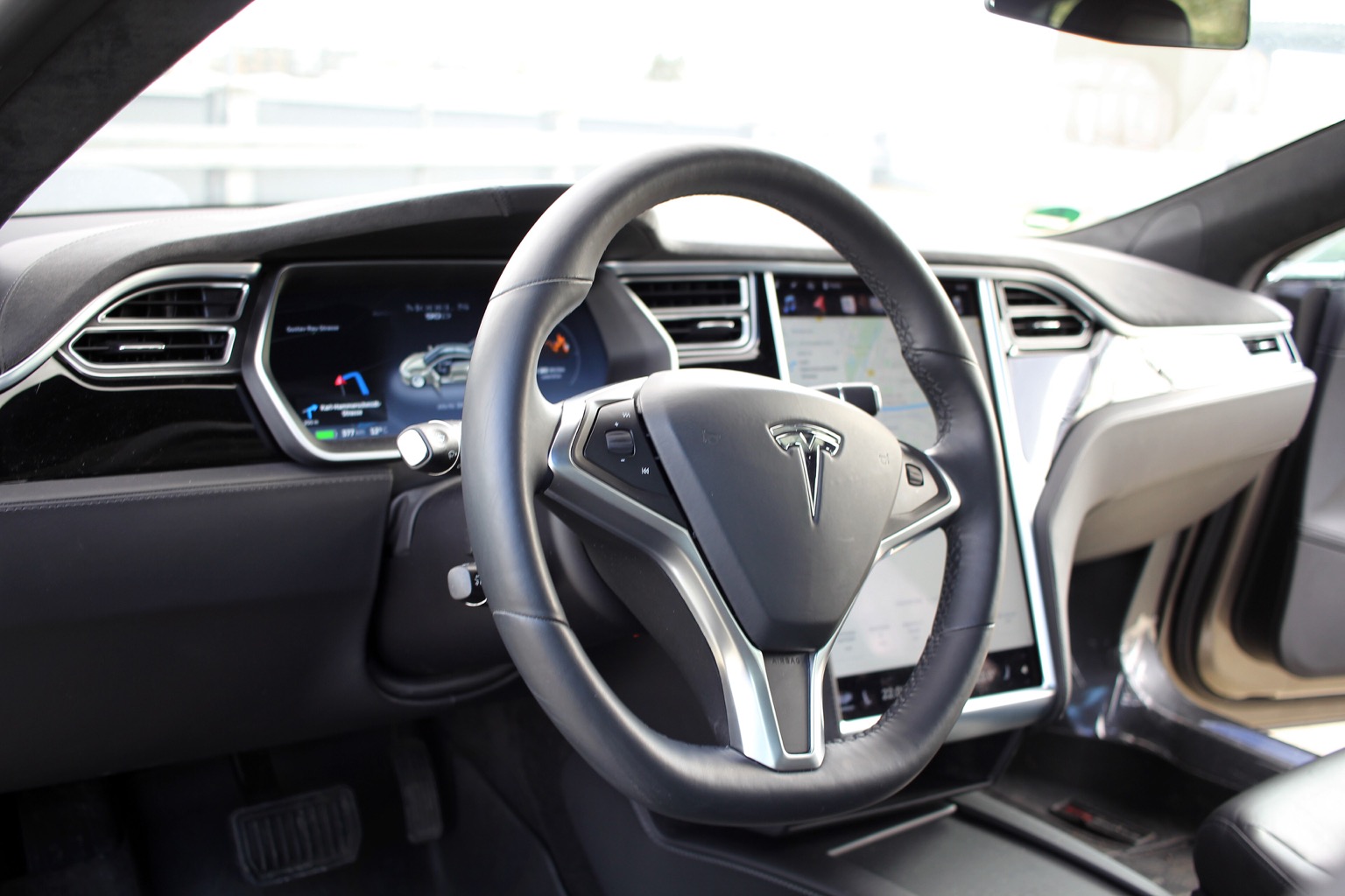 Bal kormányos Tesla Model S utastere a függőleges központi érintőképernyővel és a vezető előtti műszeregységgel